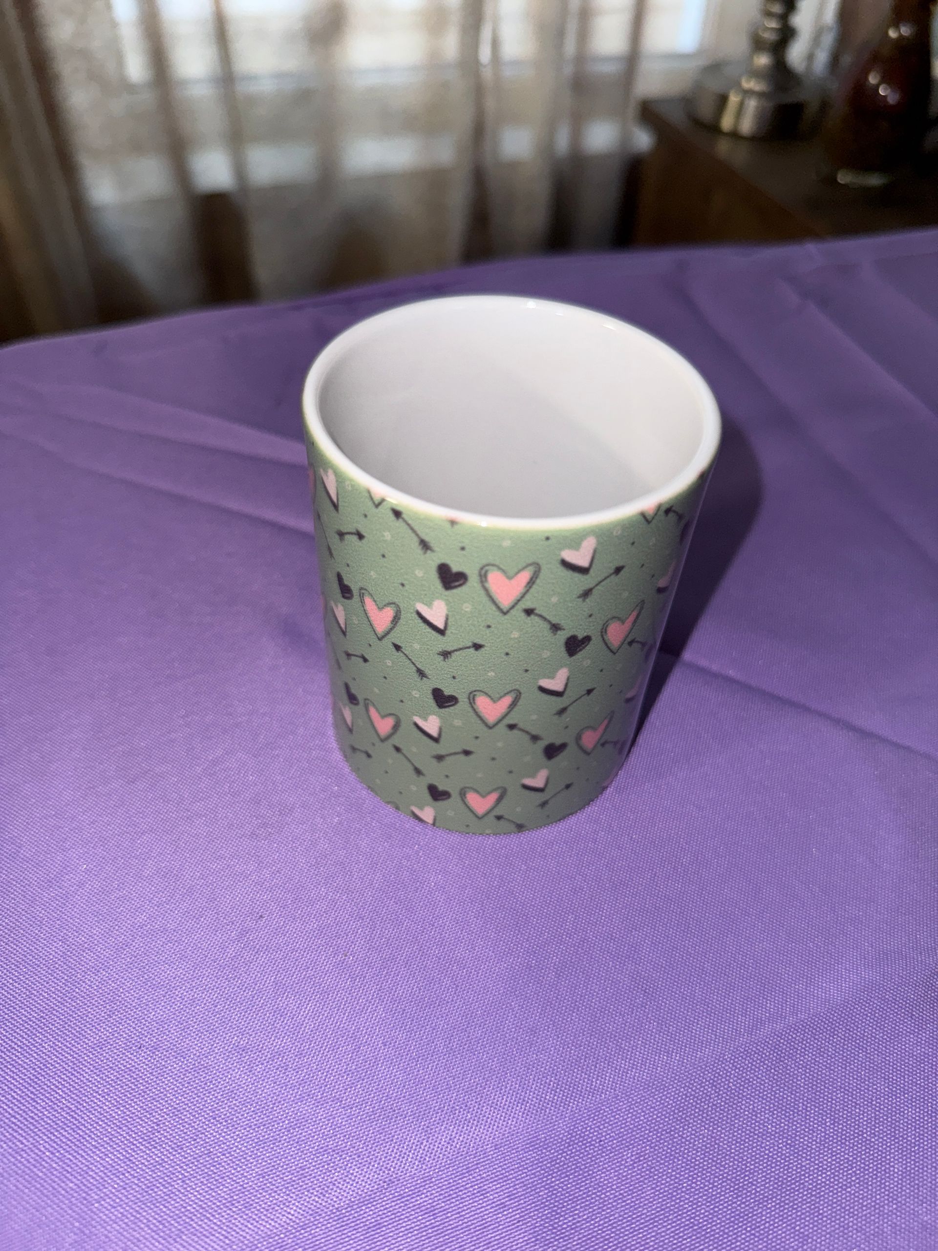 Green cup wrapped around with black pink and light, pink hearts