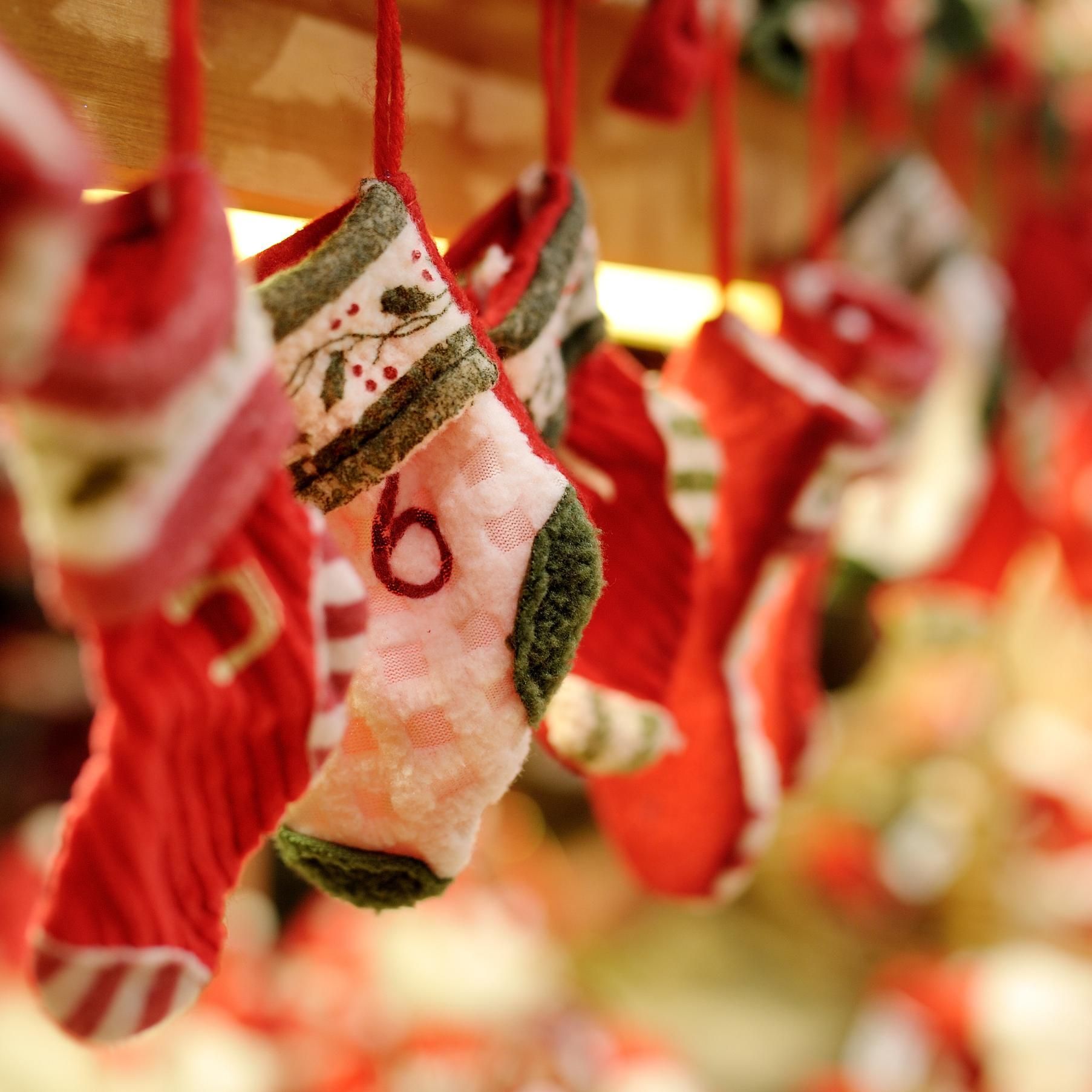 Row of red and pink Christmas stockings hanging, focus on one with a number 6.