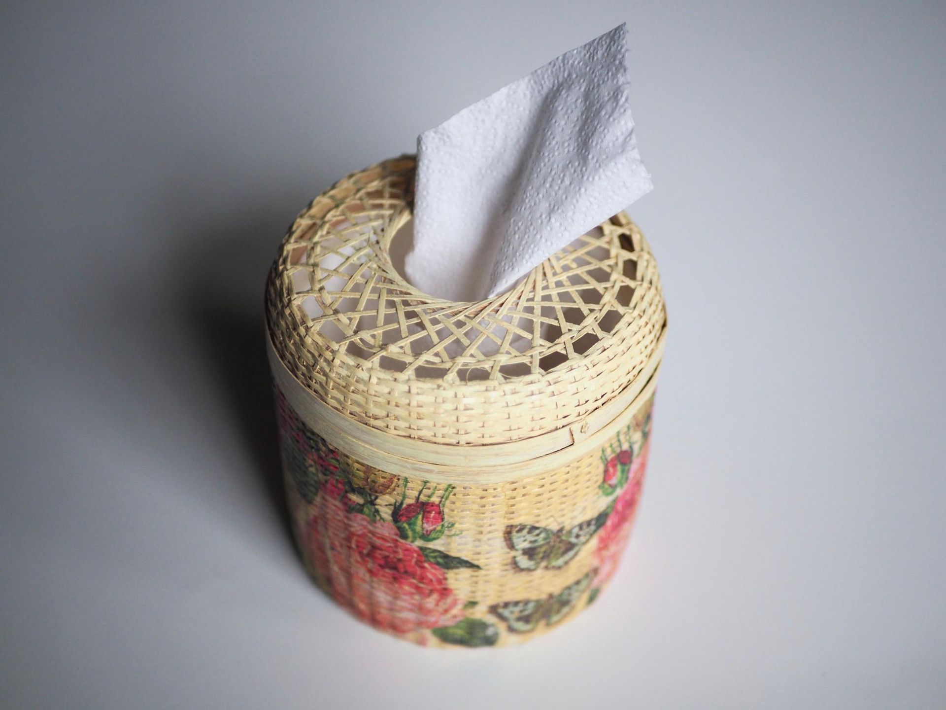 Woven tissue box with floral print, white tissue extending from the top.
