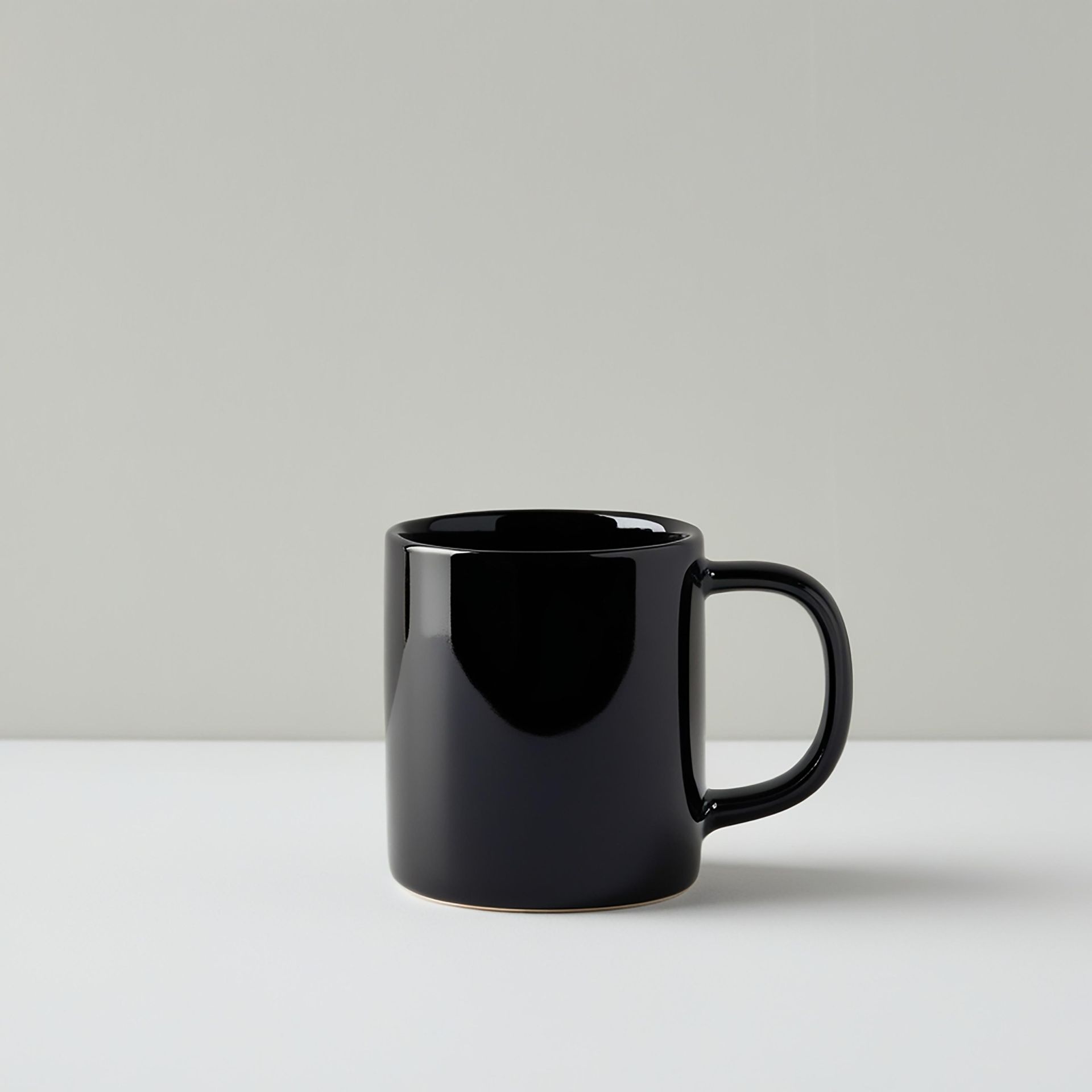 Black ceramic mug on a white surface, with a gray background.
