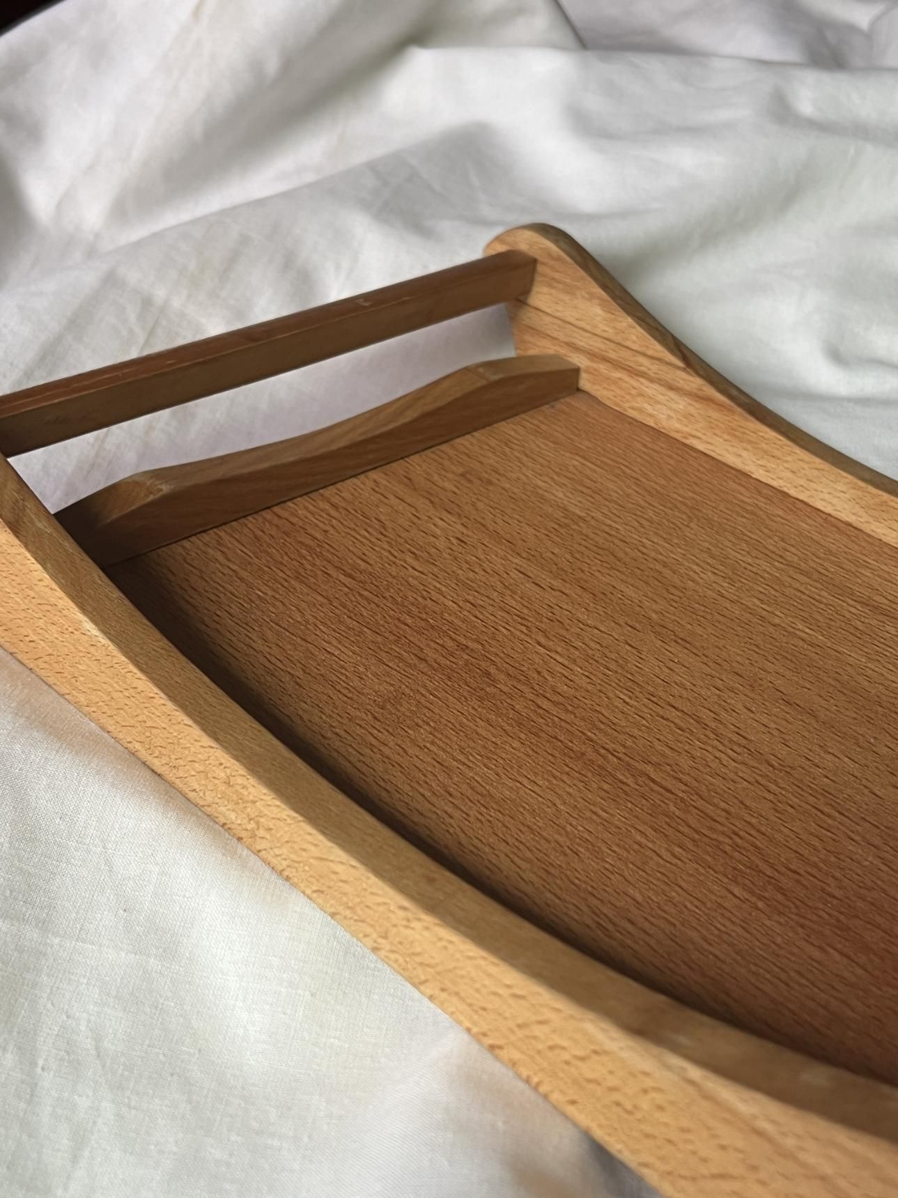 Wooden tray with a handle on a white surface.