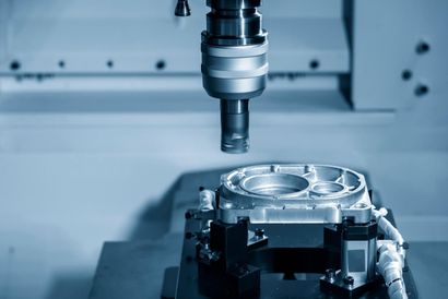 Usinage d'une pièce métallique par une machine CNC dans un atelier industriel éclairé à la lumière bleue