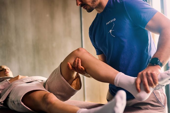 Fisioterapista esamina il ginocchio di un paziente