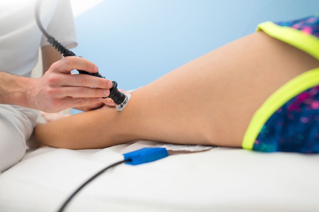 Terapista che utilizza una sonda a ultrasuoni sulla parte superiore della gamba di un paziente