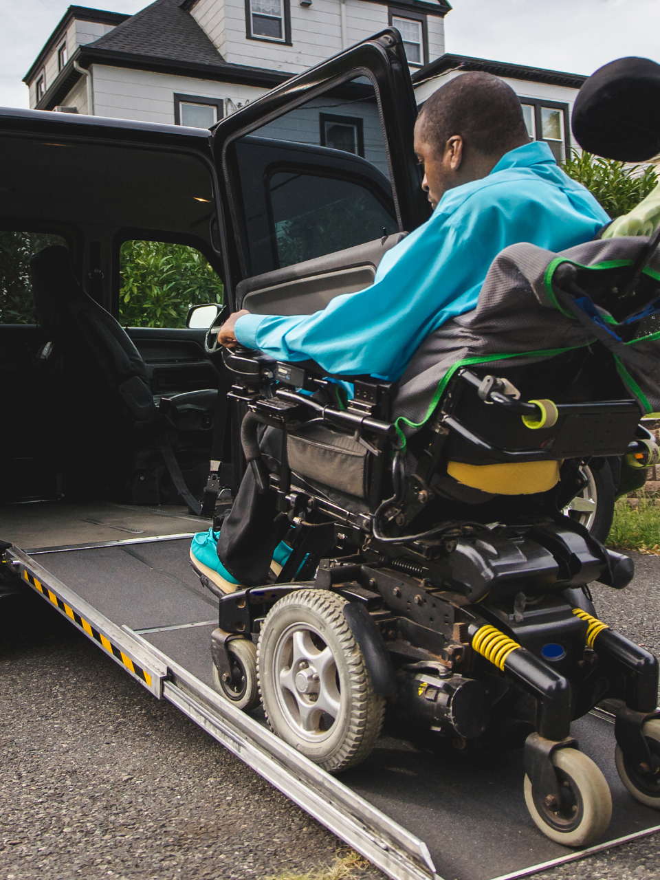 A man washes dishes in the kitchen while a boy sits on the counter, smiling and holding a dish towel.