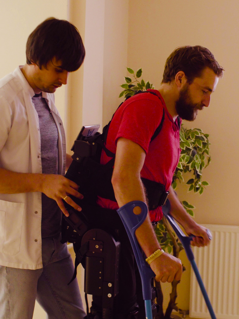 Man serves woman breakfast in living room; woman smiles, crutches near.