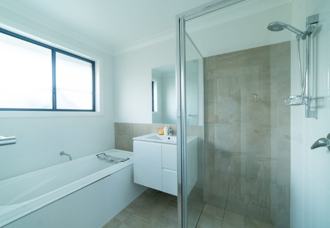Bathroom with a tub, shower, vanity, and window; light beige and white color scheme.