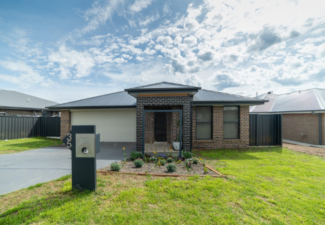 Modern brick home with gray roof and front yard.