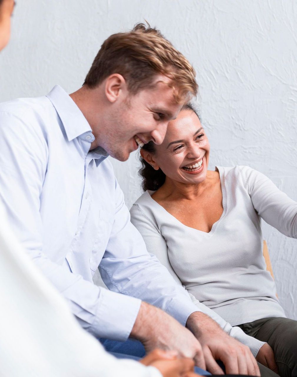 Man and woman smiling while seated, possibly in a therapy session.