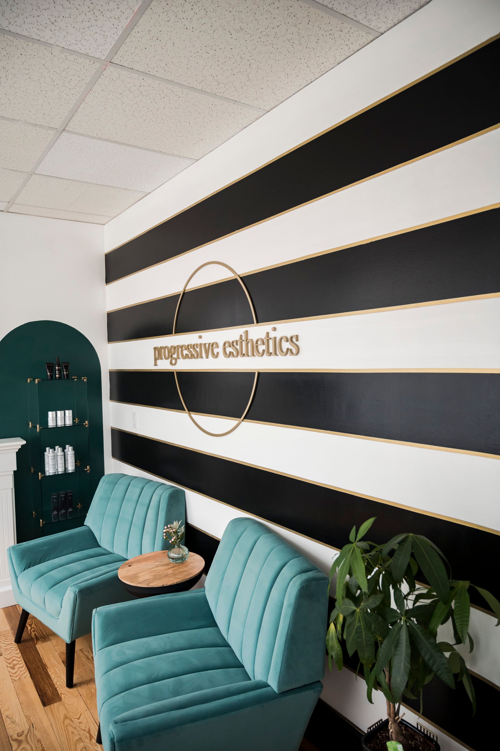 Waiting area with teal chairs, striped wall, and