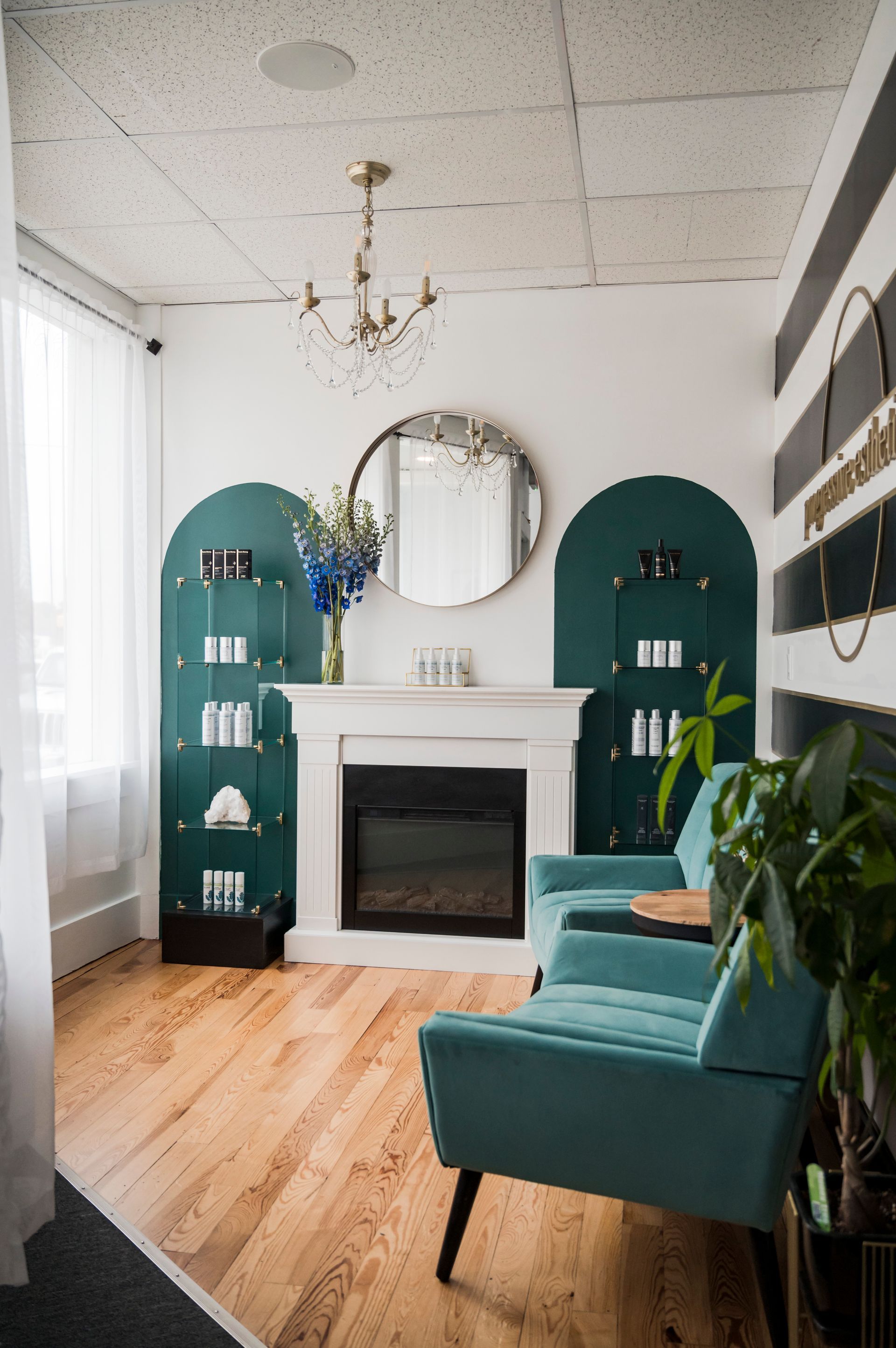 Elegant spa waiting area with teal accents, fireplace, and product displays.
