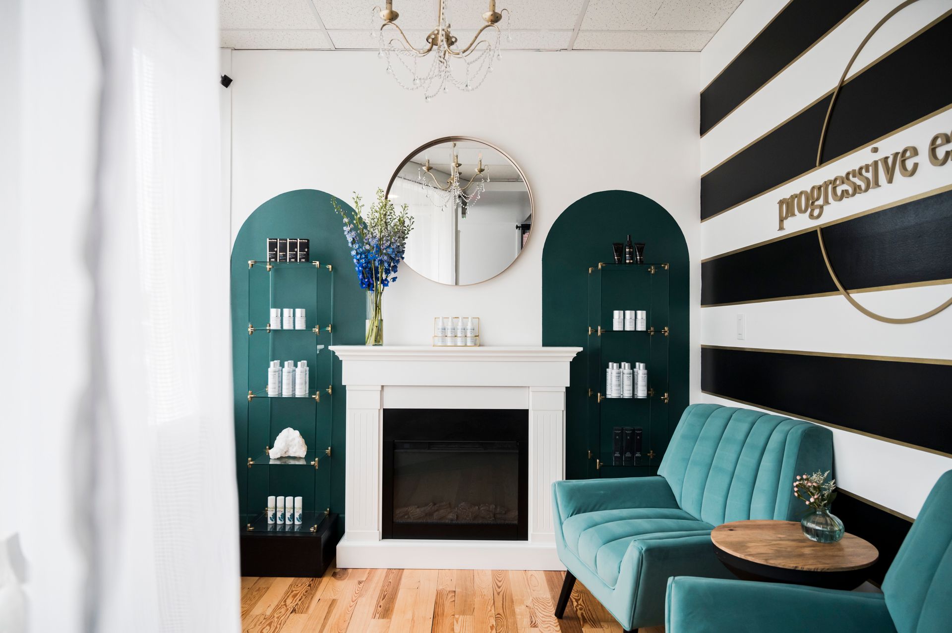 A stylish spa reception area with teal furniture, a fireplace, and product displays.