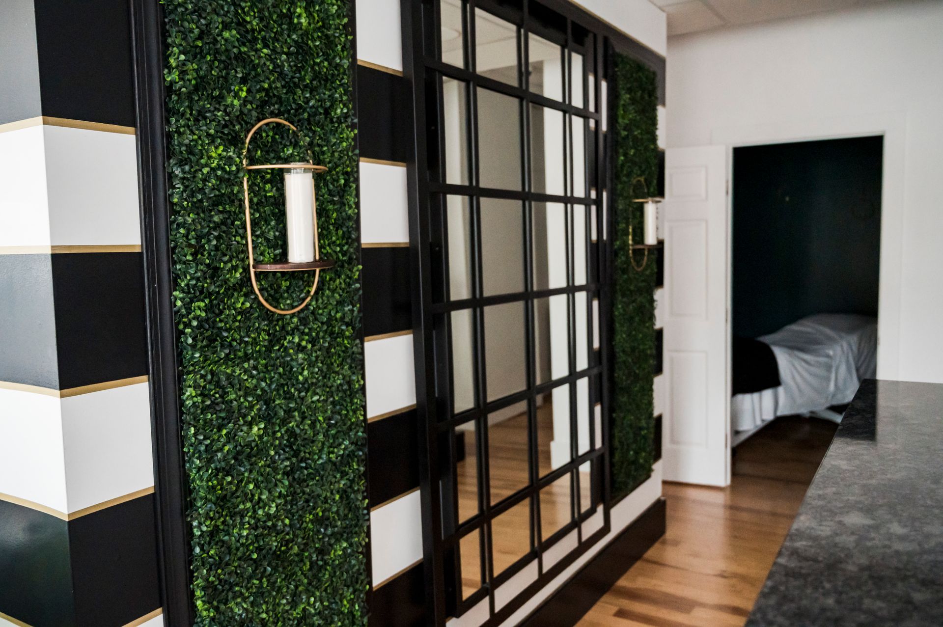 Hallway with black and white striped wall, green wall panel, framed window, and doorway.