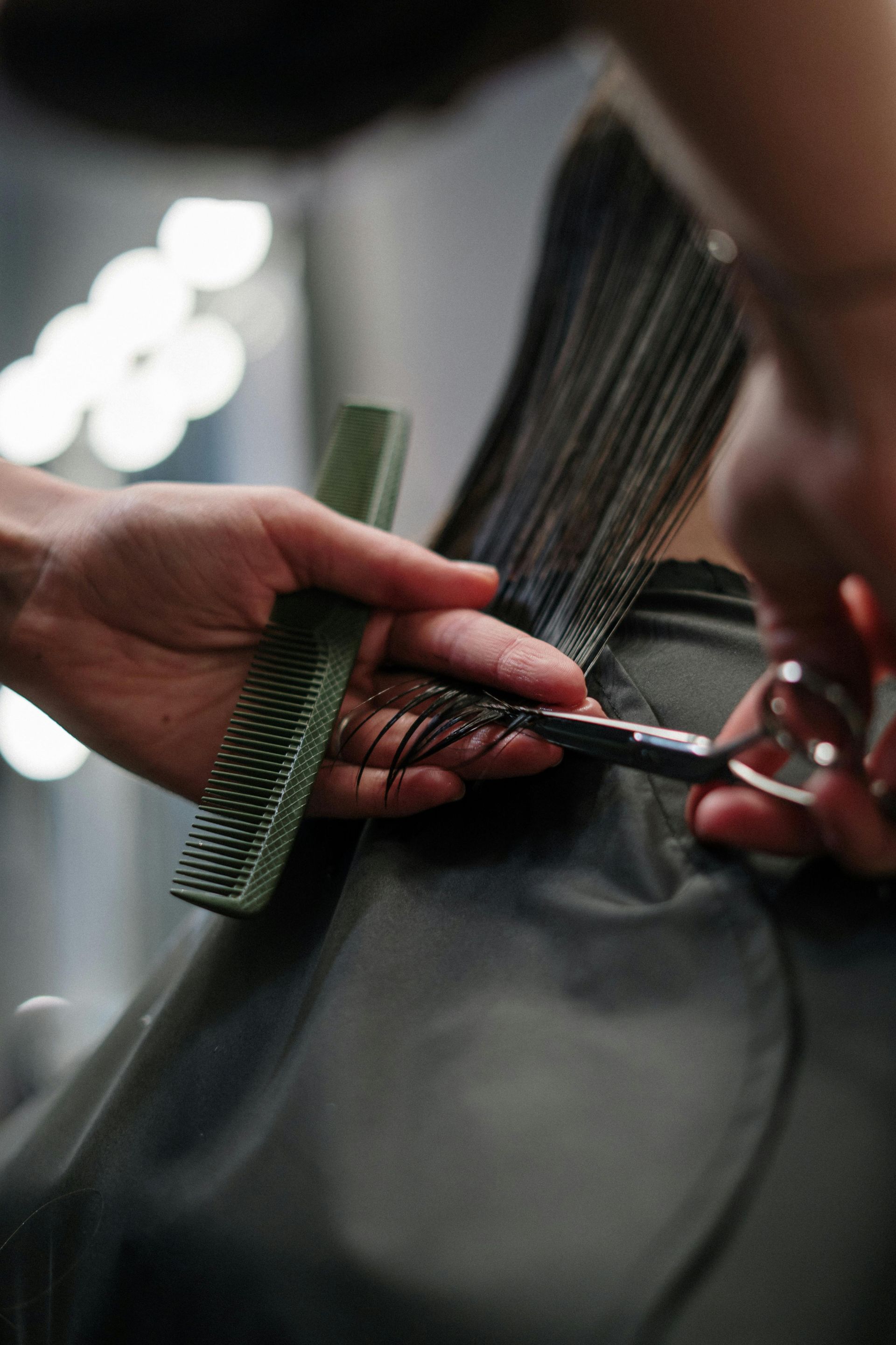 Hairdresser cutting hair with scissors and a comb in a salon.