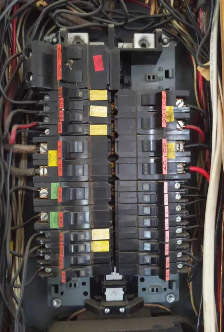 Close-up view of an electrical panel featuring several white contactors and circuit breakers with wired connections.