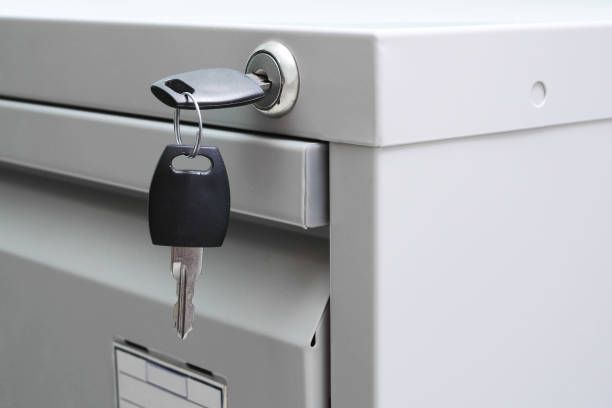 A key is hanging from the lock of a filing cabinet.