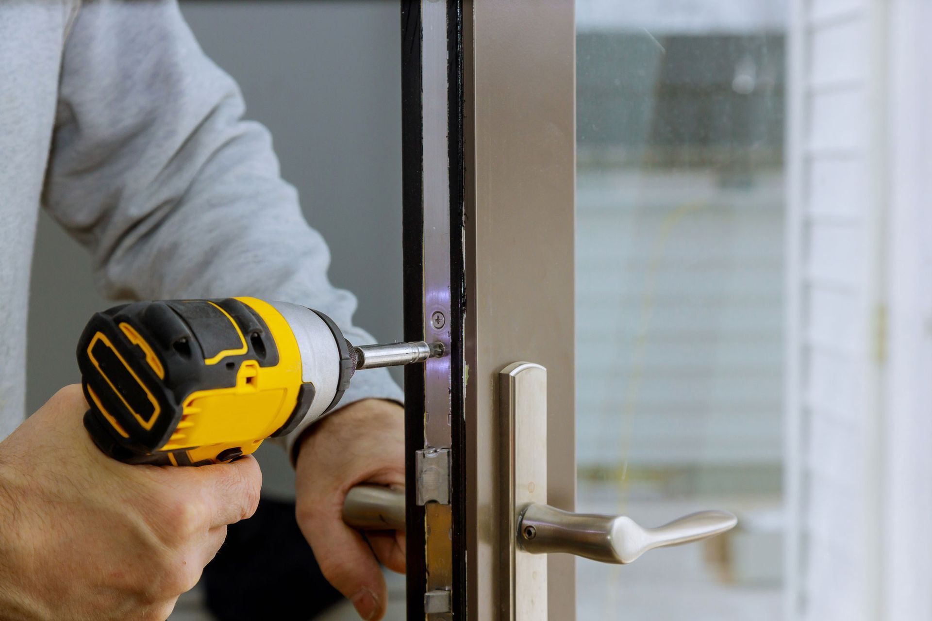 A man is using a drill to fix a door lock.