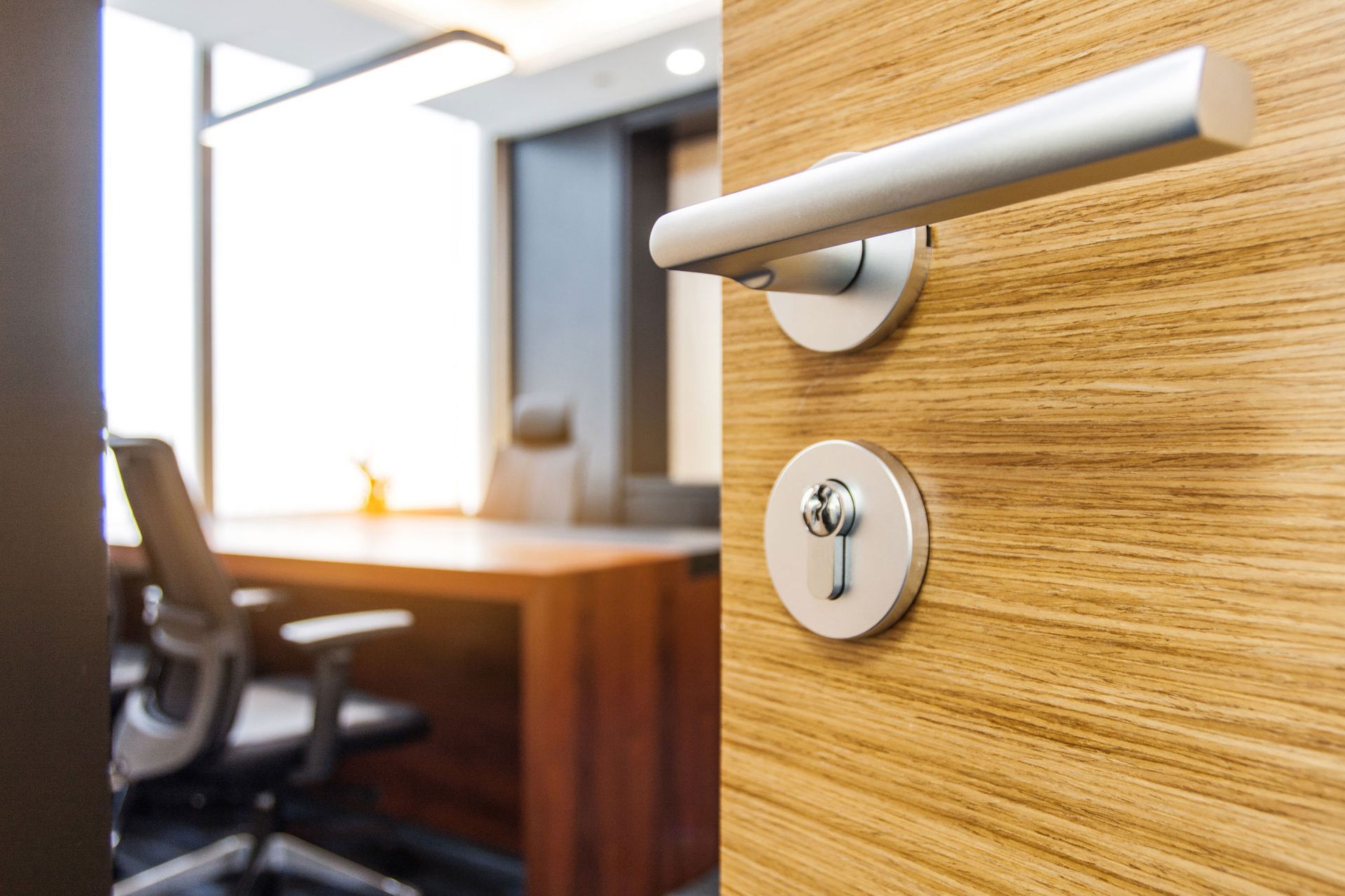 A wooden door with a key in it is open to an office.