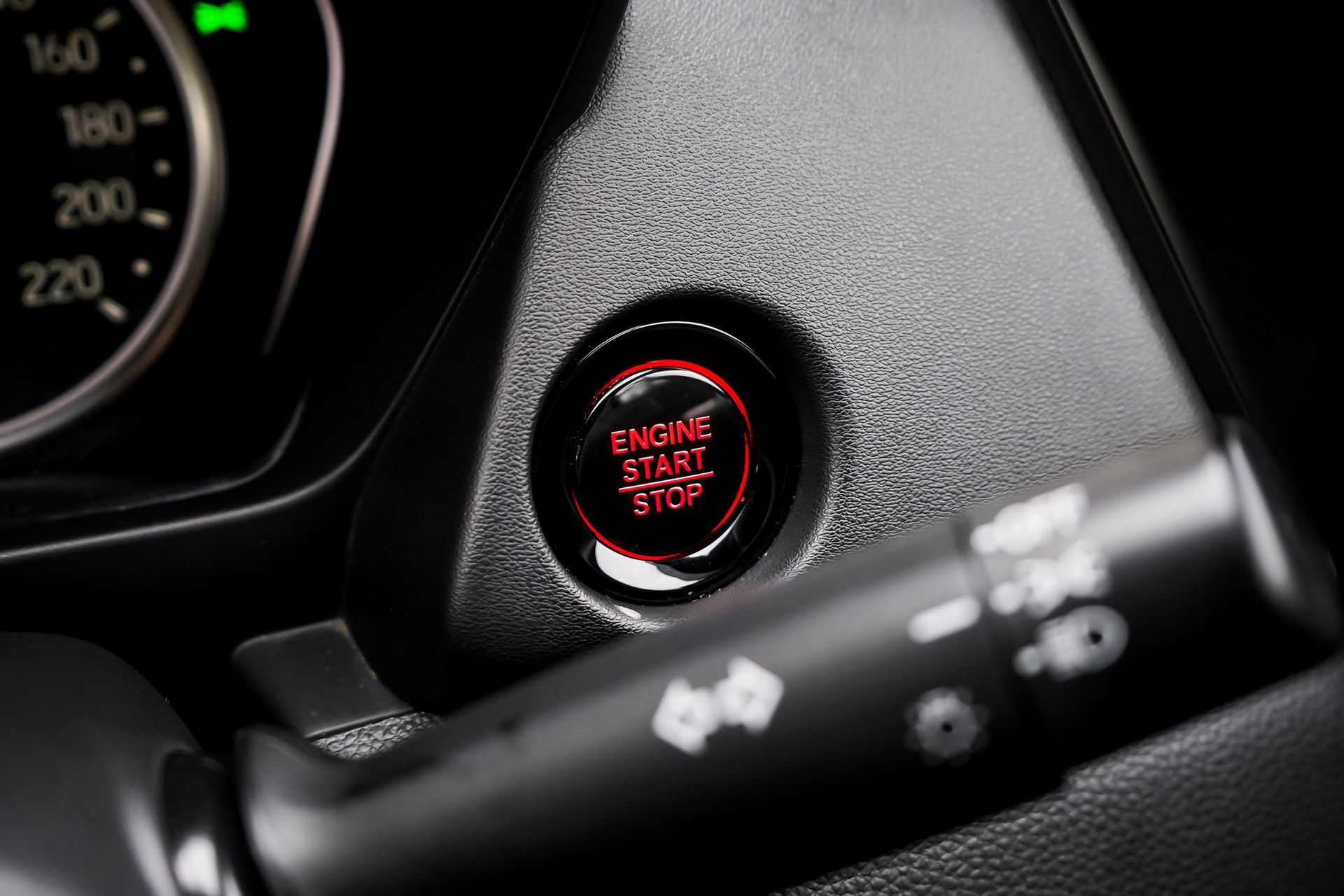 A close up of a car's engine start stop button.