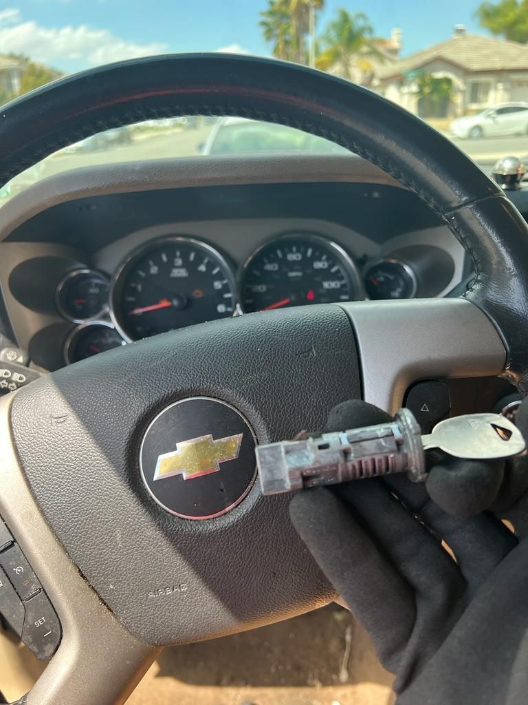A person is holding a key in front of a Chevrolet steering wheel.