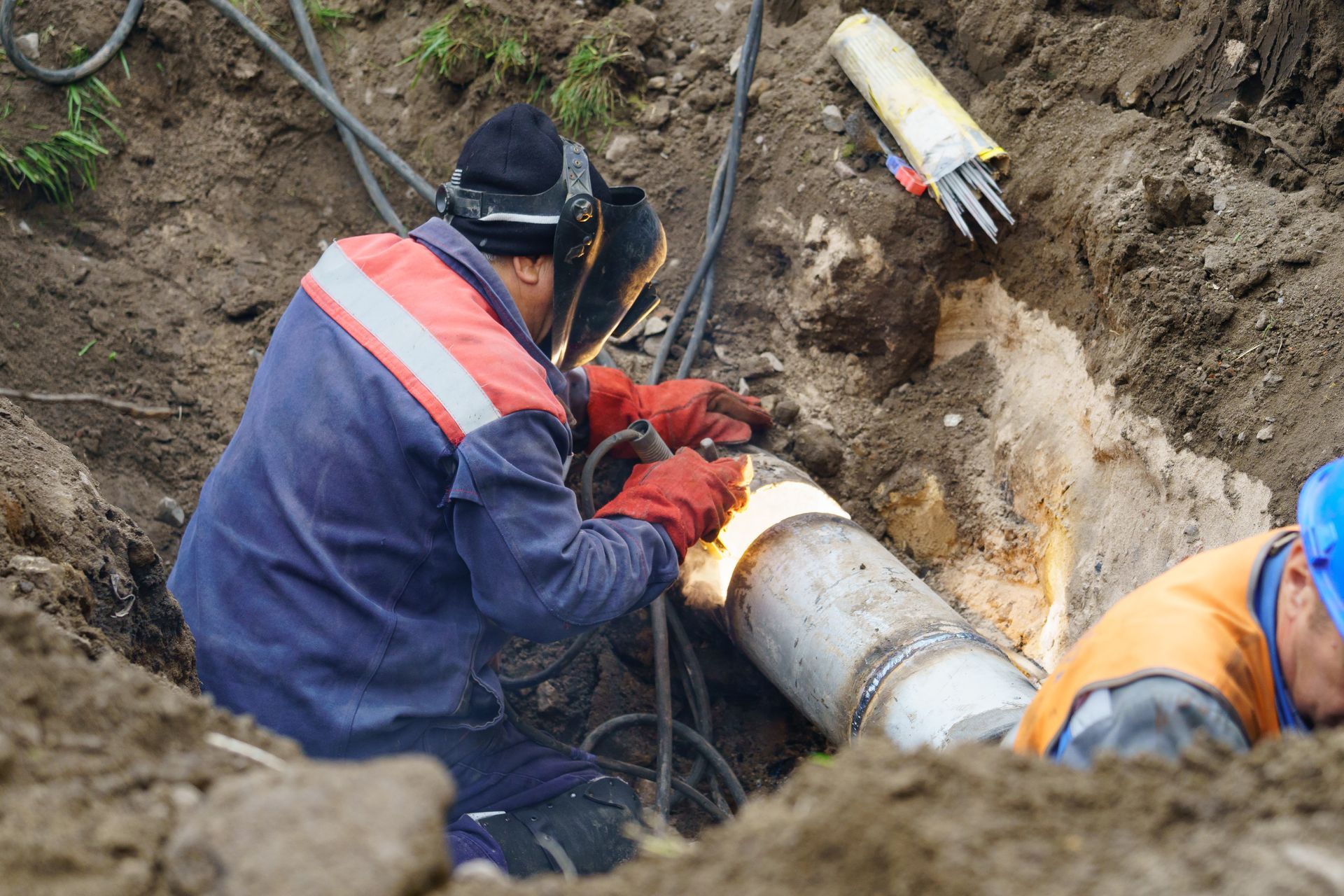 Utility worker performing welding repairs on a broken water main to replace deteriorated sections of the water pipe.of water pipe.