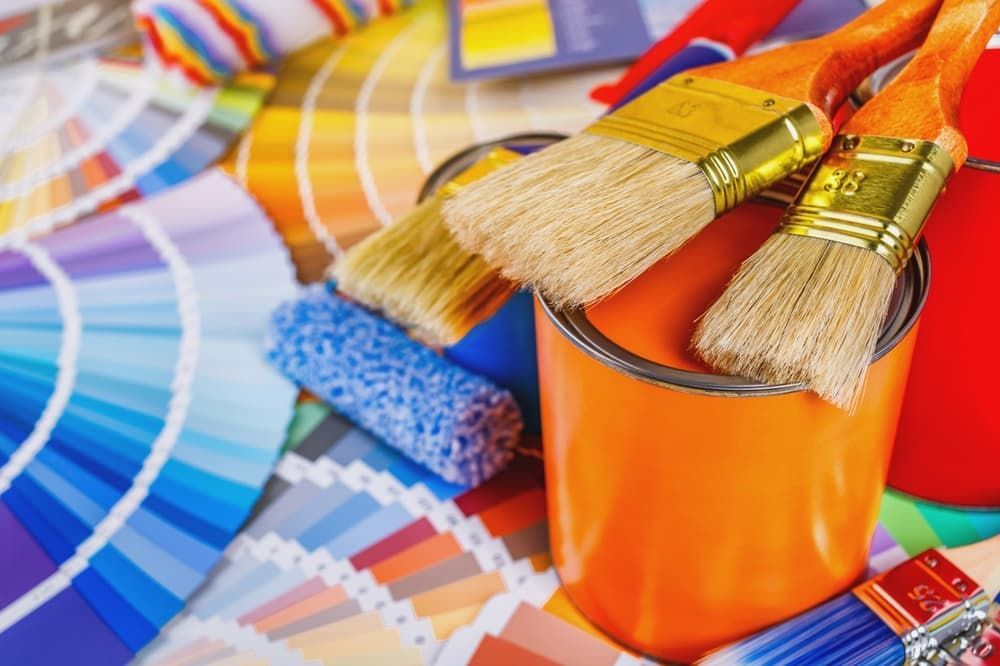 Paintbrushes rest on a can of orange paint.