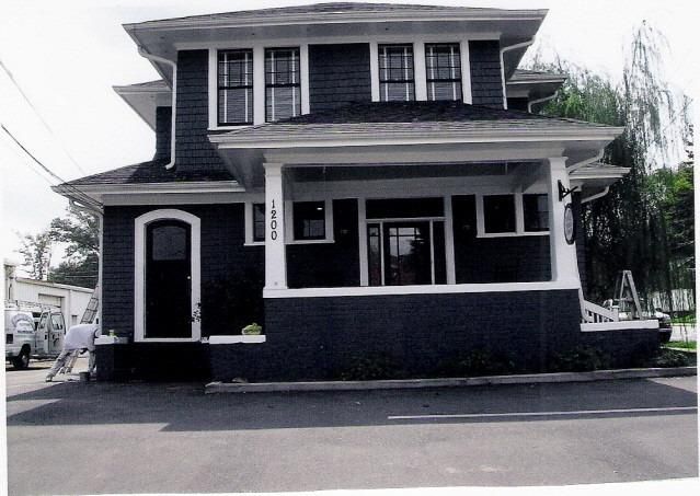 Two-story dark blue house with white trim, porch, and windows.
