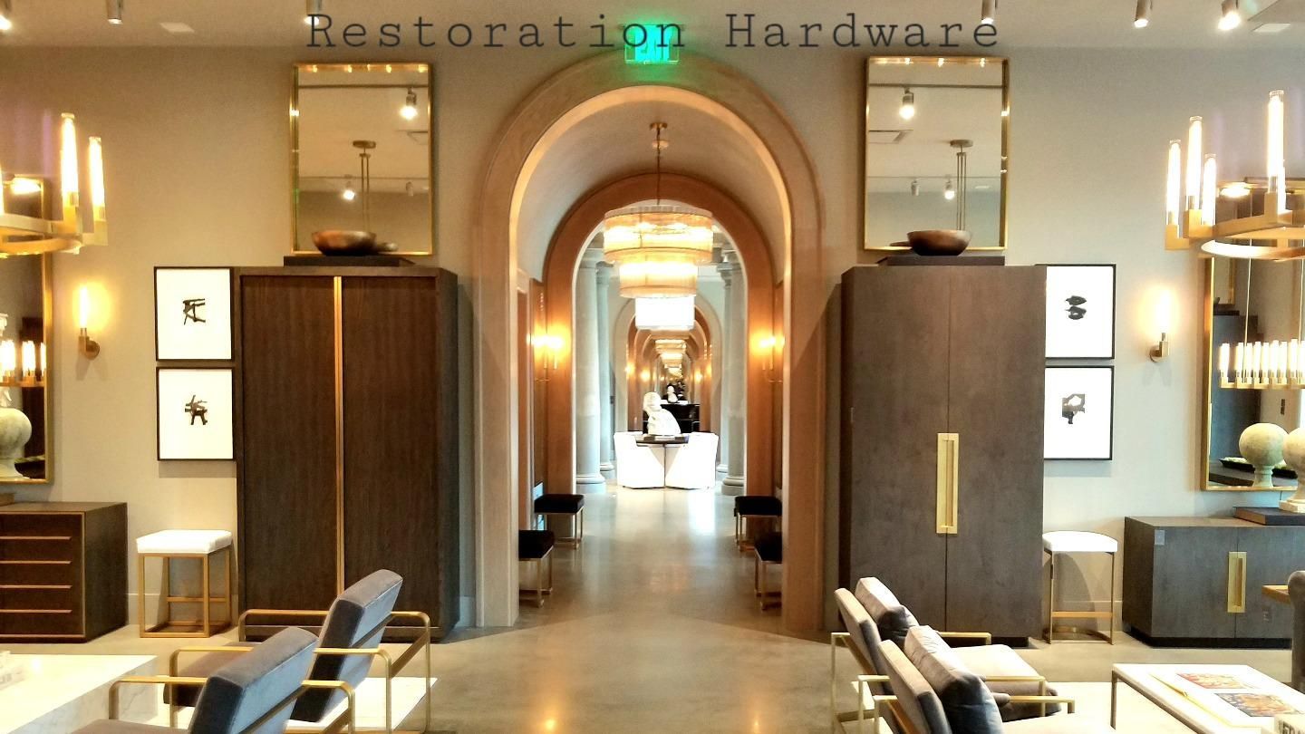 Restoration Hardware showroom interior with arched doorways, mirrors, and furniture.