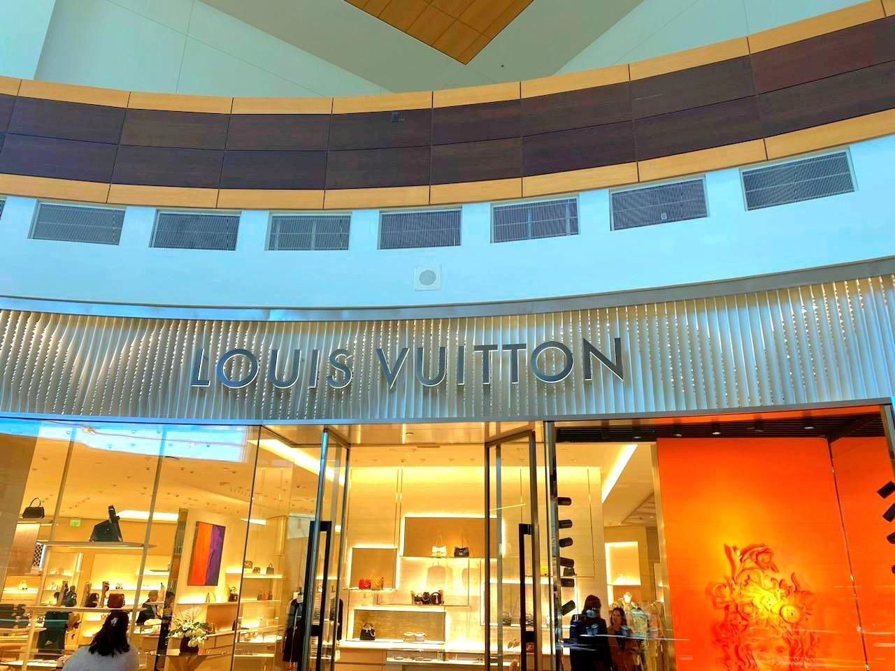 Louis Vuitton store entrance with illuminated logo; warm lighting.