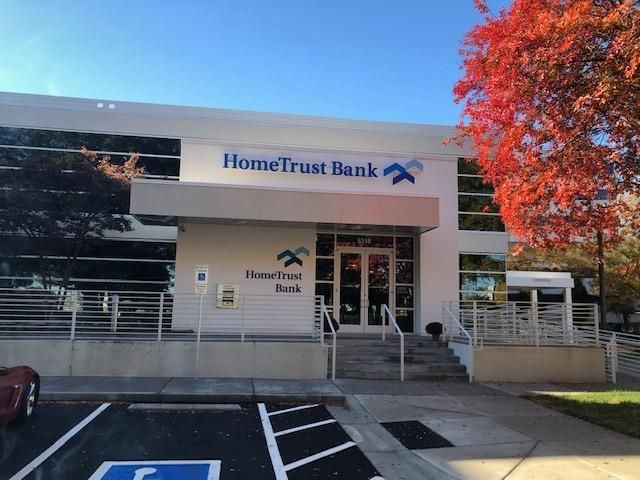 HomeTrust Bank building exterior with blue sky and autumn tree.
