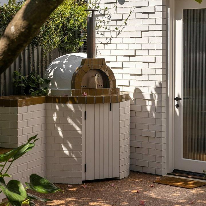 Brick Oven is Sitting Outside of a White Brick Building — Beith Building & Developments Pty Ltd In Burleigh Heads, QLD