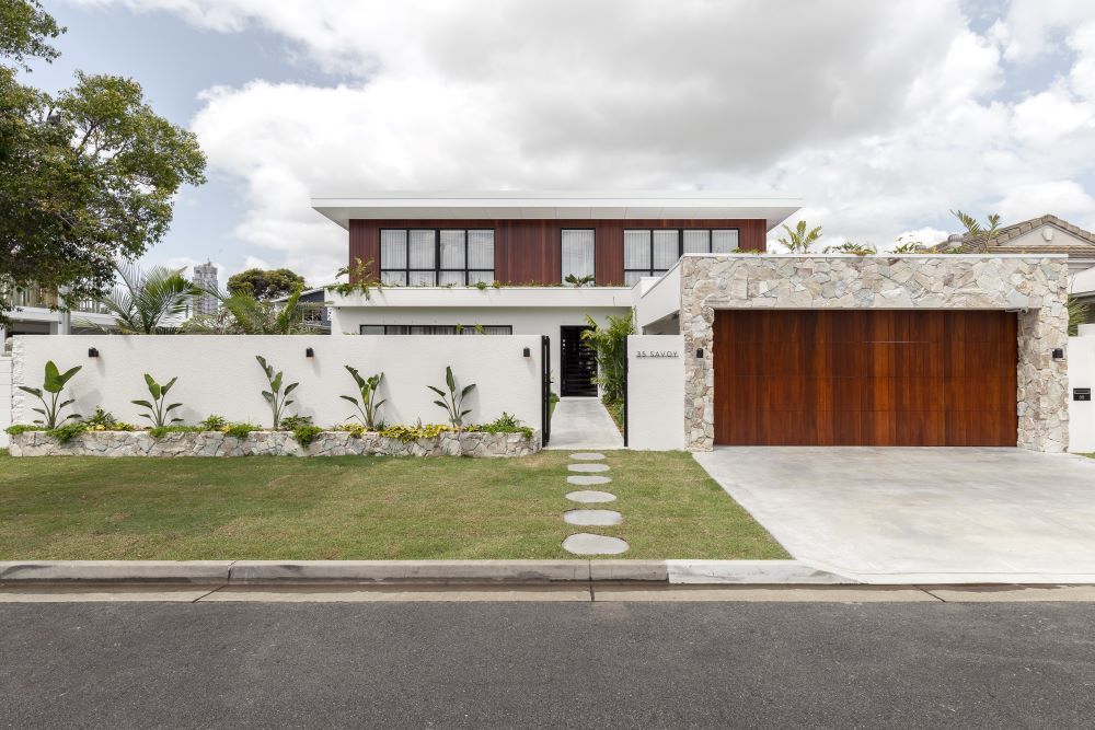A Modern House With a Wooden Garage Door and a Stone Wall — Beith Building & Developments Pty Ltd In Burleigh Heads, QLD