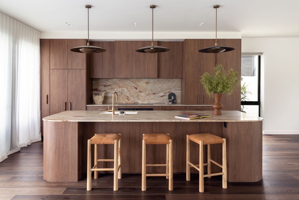 A Kitchen With Wooden Cabinets and Stools and a Large Island — Beith Building & Developments Pty Ltd in Burleigh Heads, Qld
