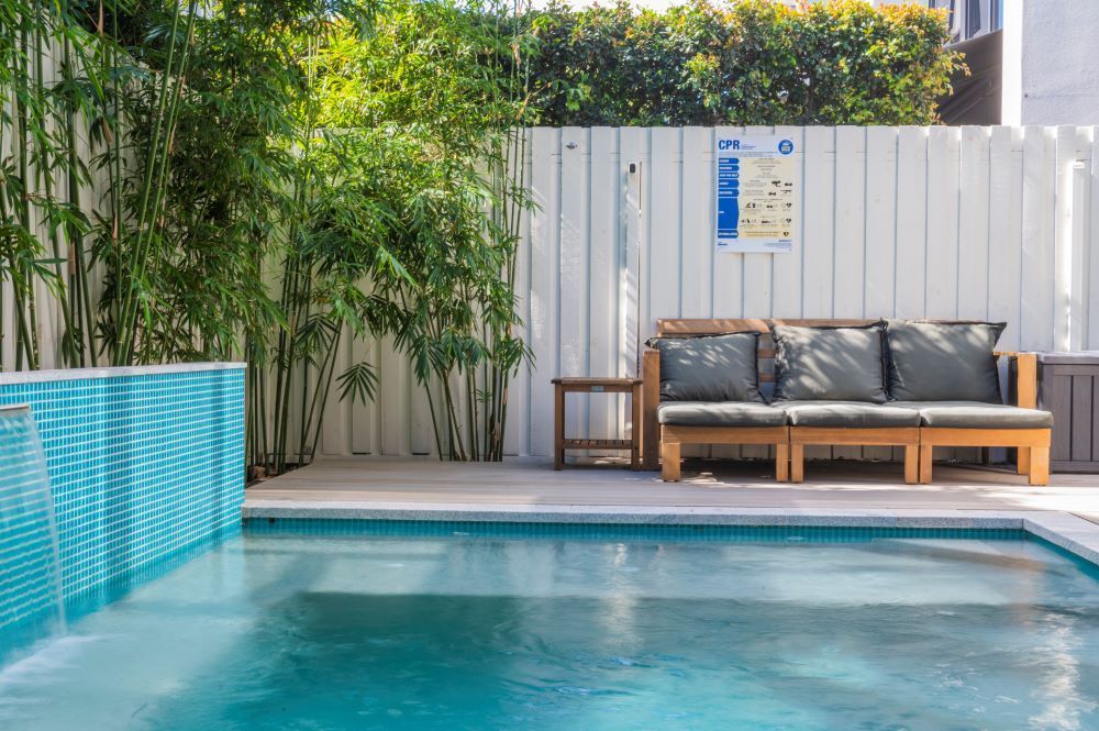 A Swimming Pool With a Couch and a Table Next to It — Beith Building & Developments Pty Ltd In Burleigh Heads, QLD