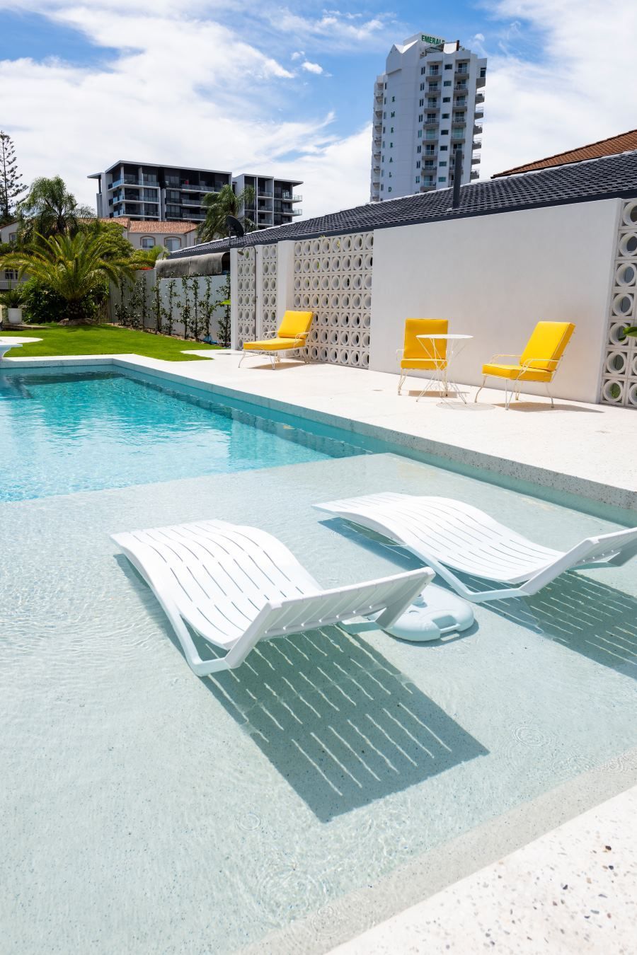 Two white lounge chairs are sitting next to a large swimming pool.