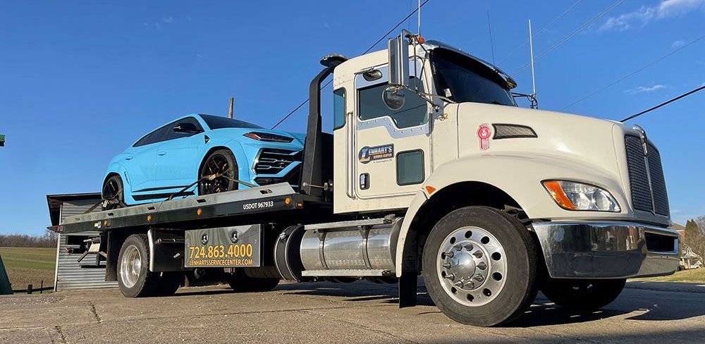 a white tow truck is carrying a blue sports car
