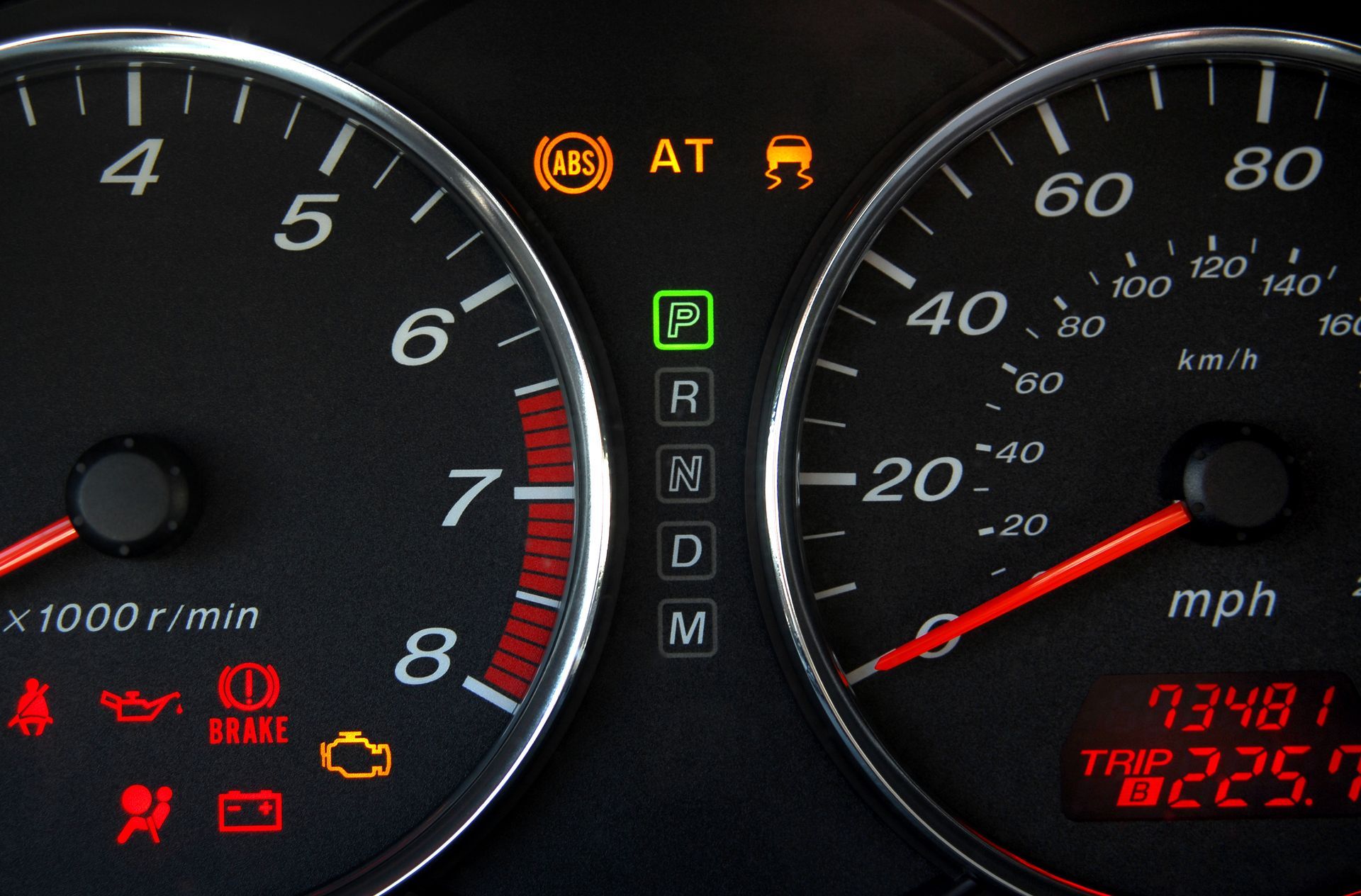 A close up of a car dashboard with a warning light that says at