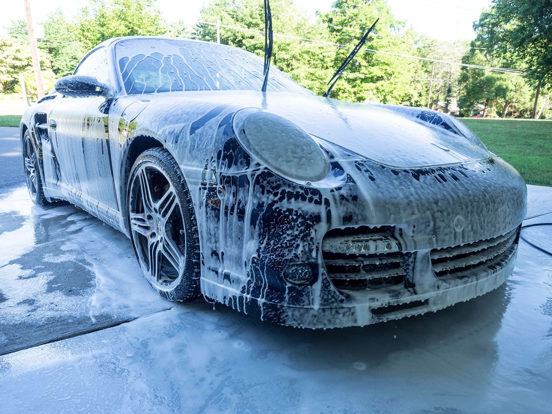 A porsche 911 turbo is covered in foam while being washed.