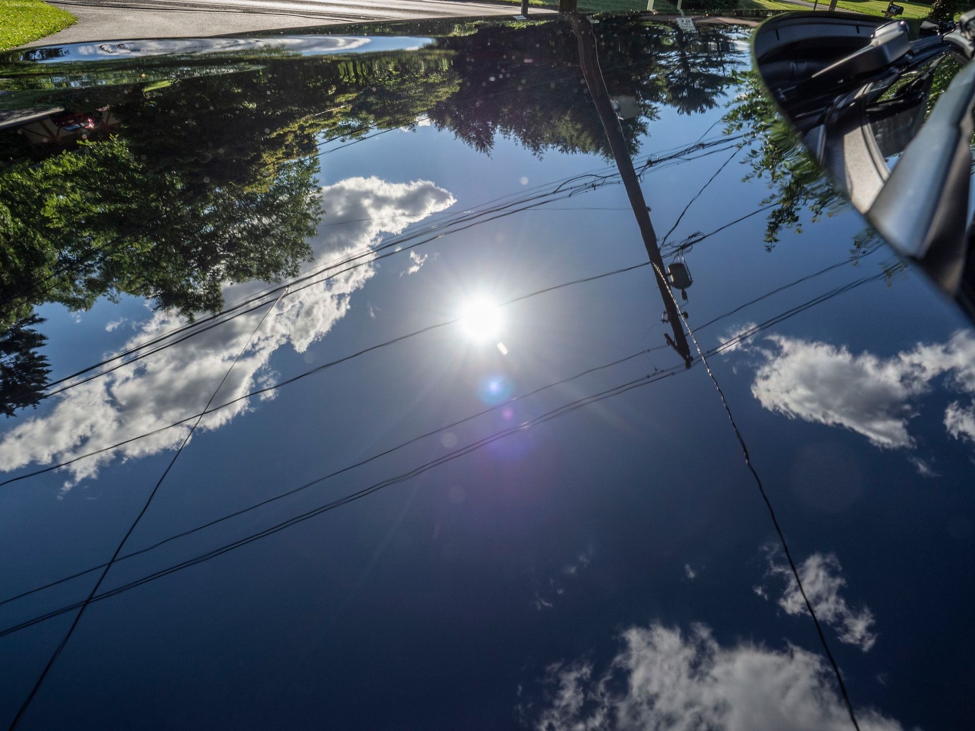 The sun is reflected in the hood of a car