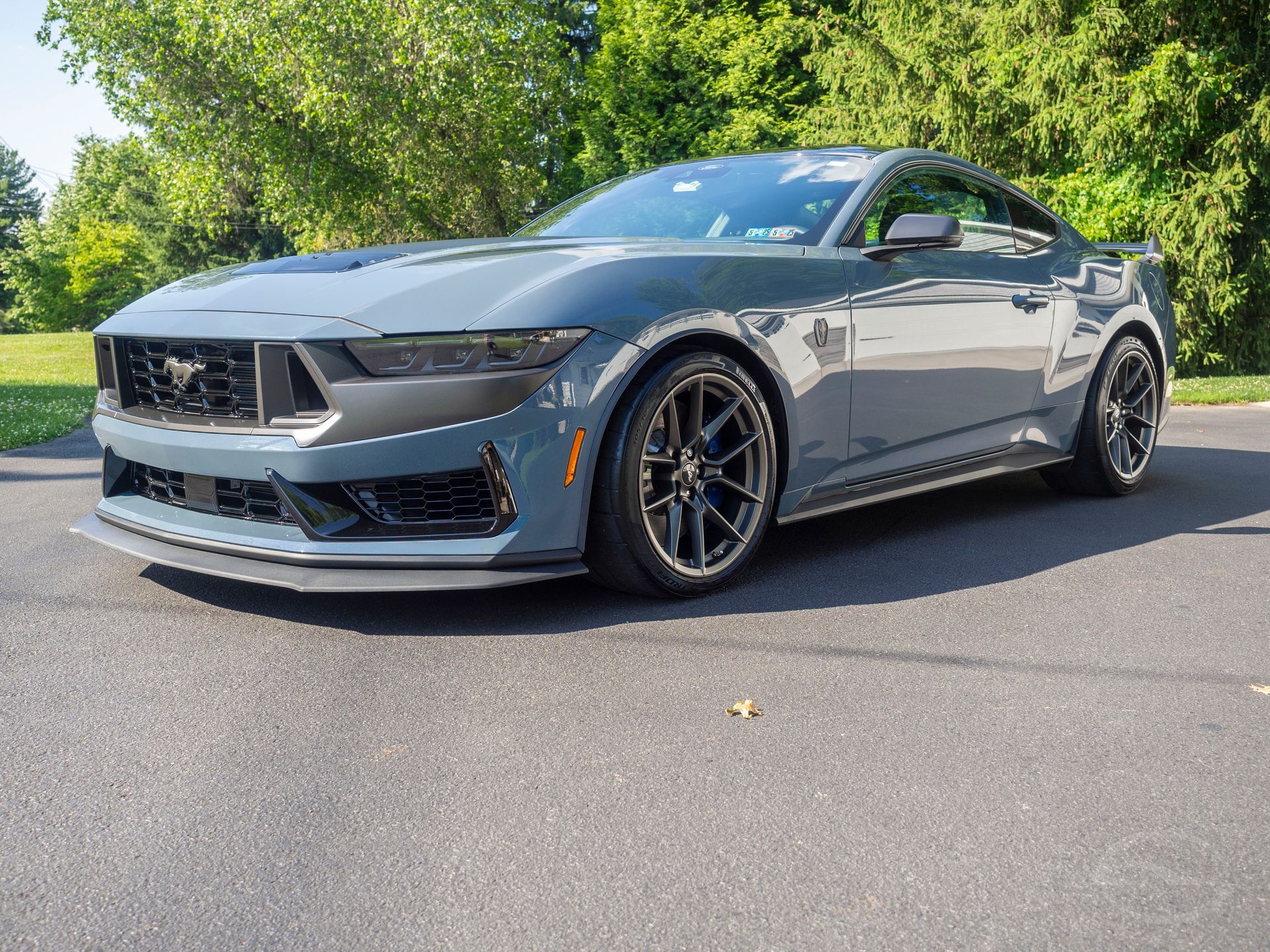 A gray ford mustang is parked on the side of the road.
