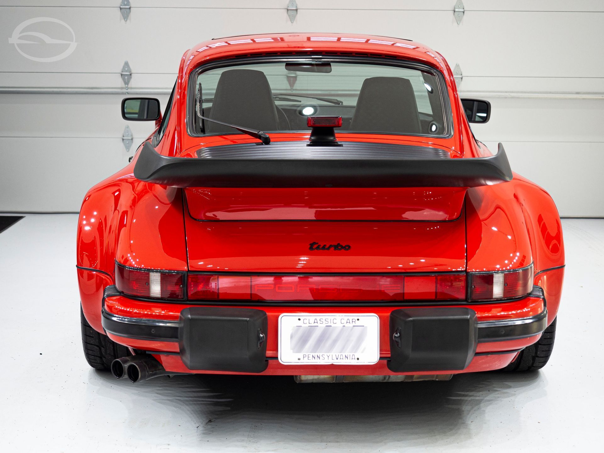 A silver bmw is being painted in a garage with yellow lights.