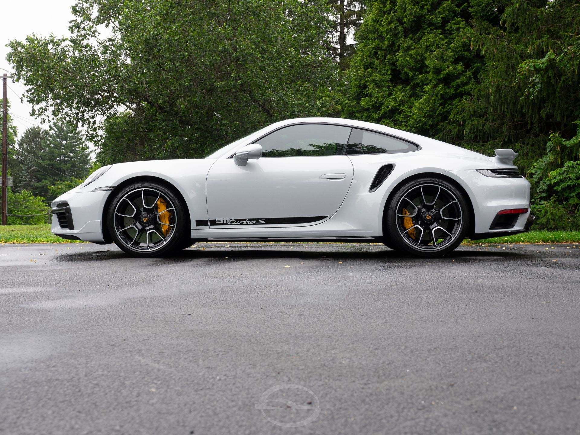 A white porsche 911 turbo s is parked in a parking lot.