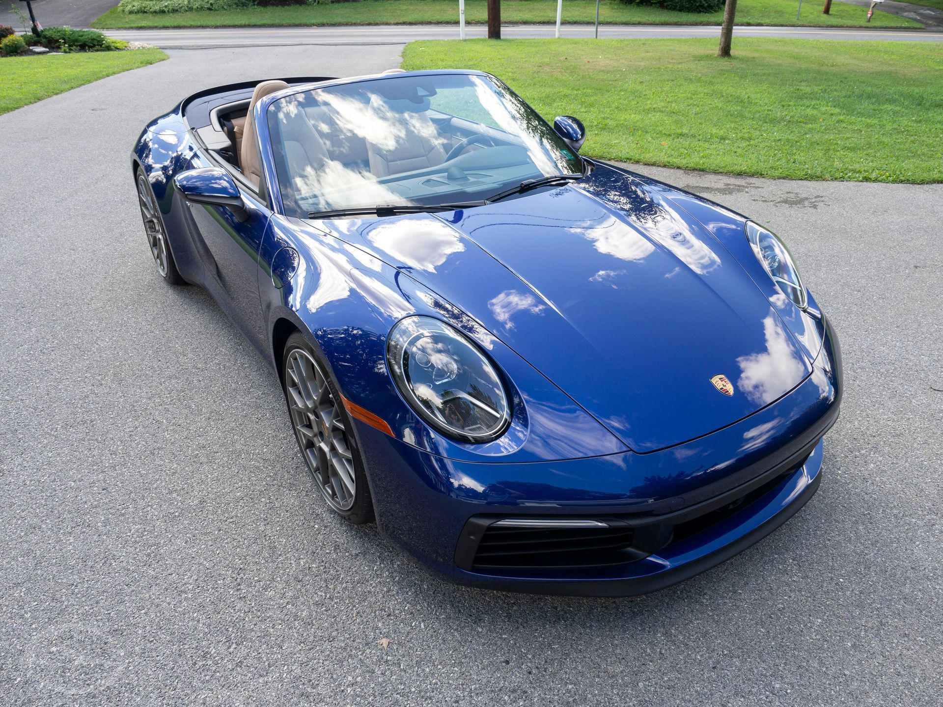 A blue porsche 911 carrera is parked in a driveway.