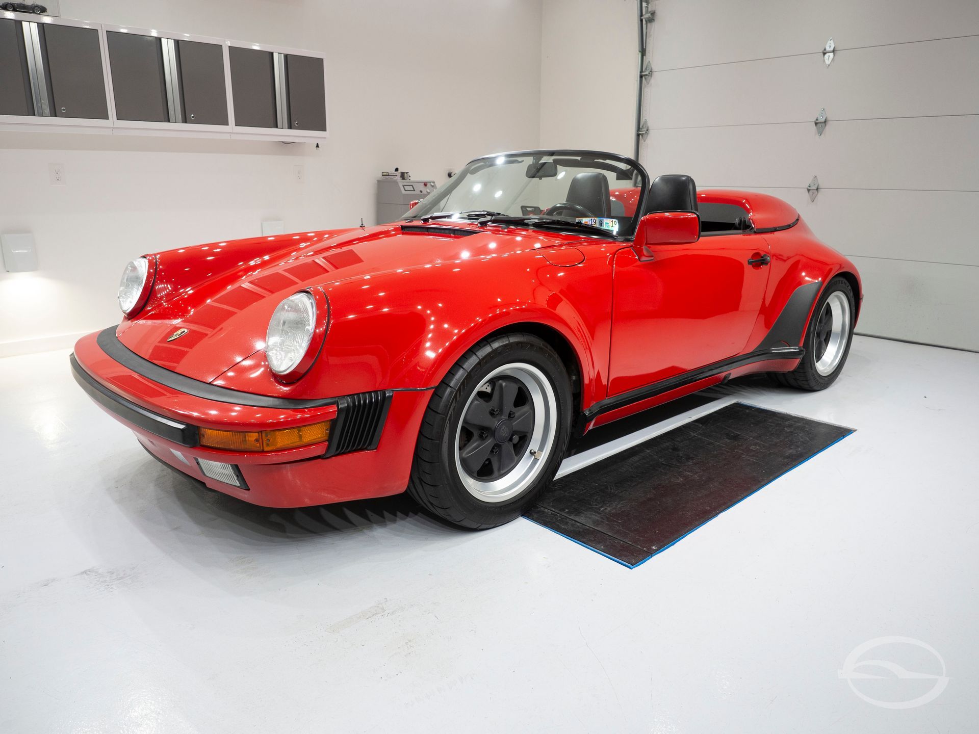 A red porsche convertible is parked in a garage.