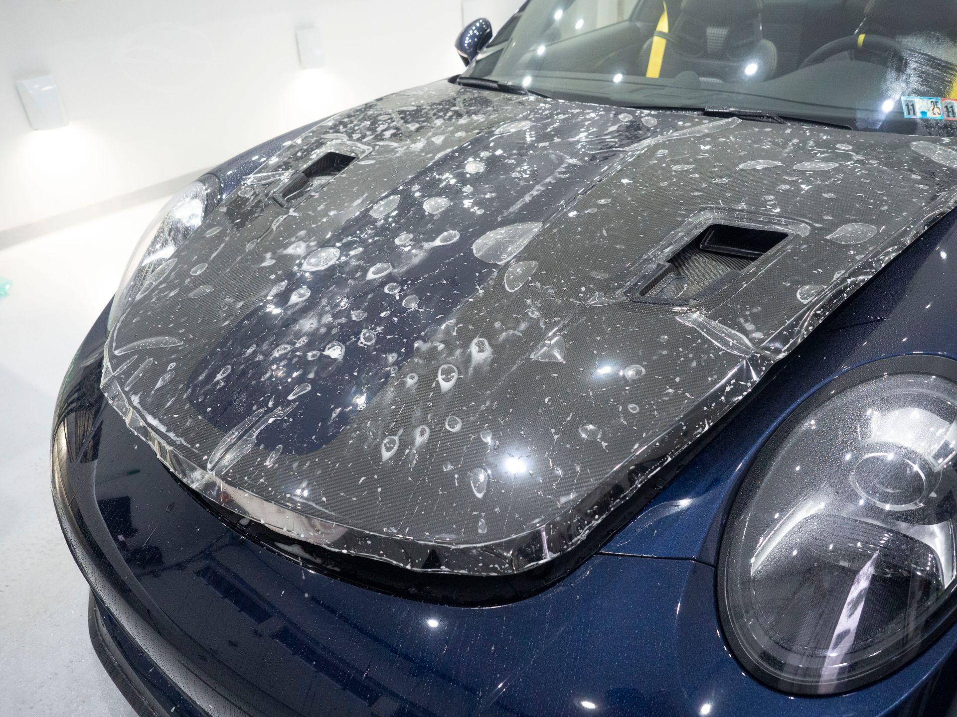 A close up of a car with a protective film on the hood.