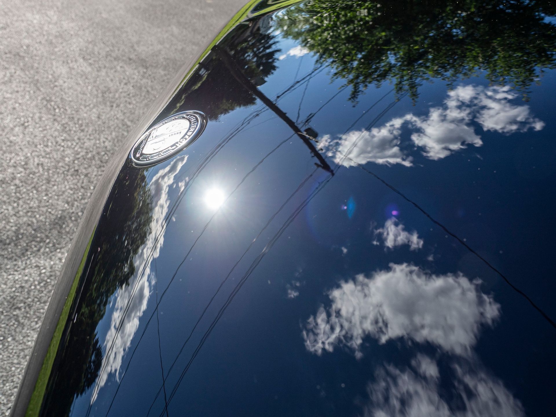 The sun is reflected in the hood of a car