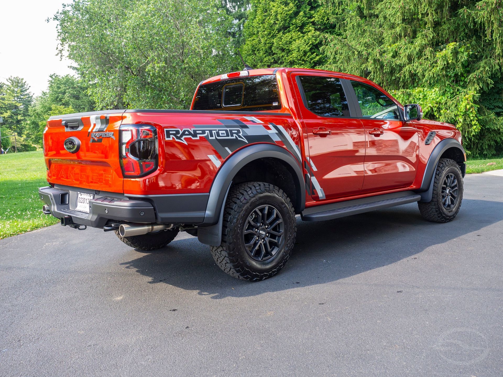 A red ford raptor truck is parked on the side of the road.