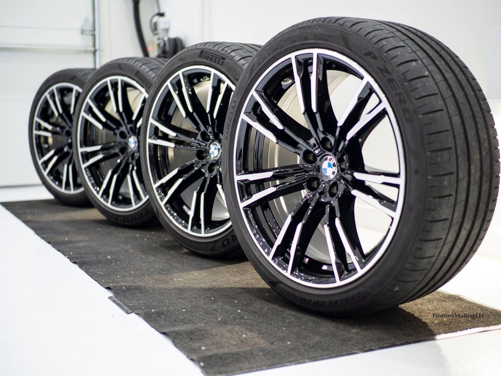 A row of bmw wheels and tires are lined up on a mat.
