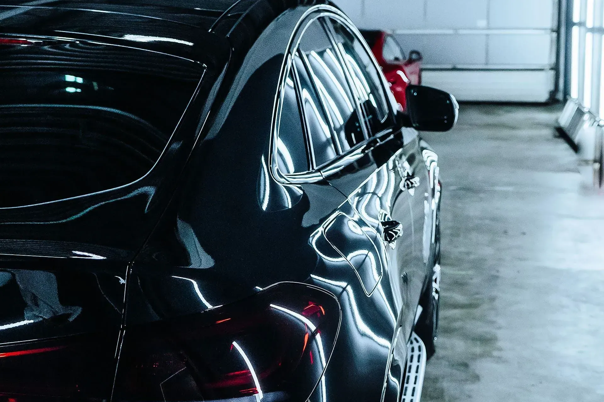 Black car in a garage with a reflective surface.