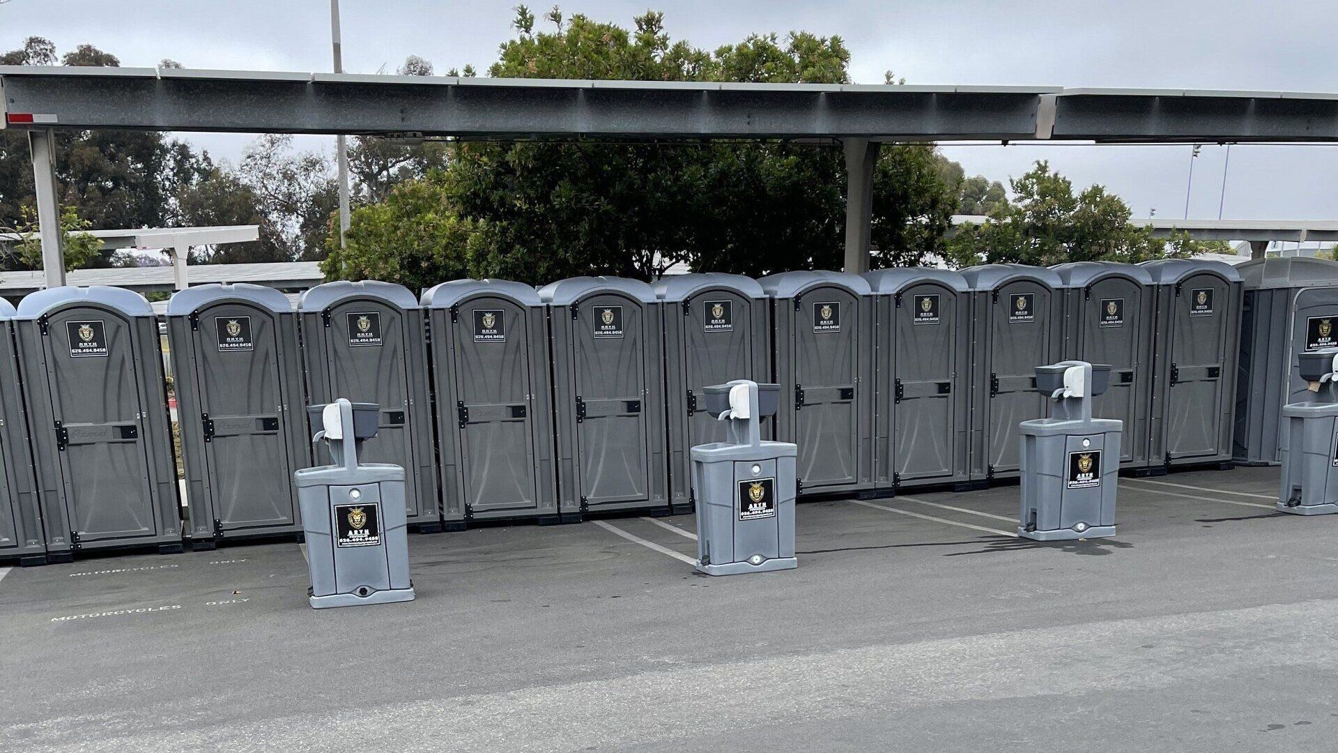 A row of portable toilets are lined up in a parking lot.